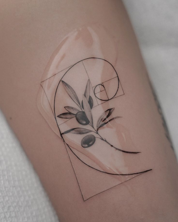 Geometric olive branch tattoo on arm with Fibonacci spiral design, showcasing minimalistic black ink style.